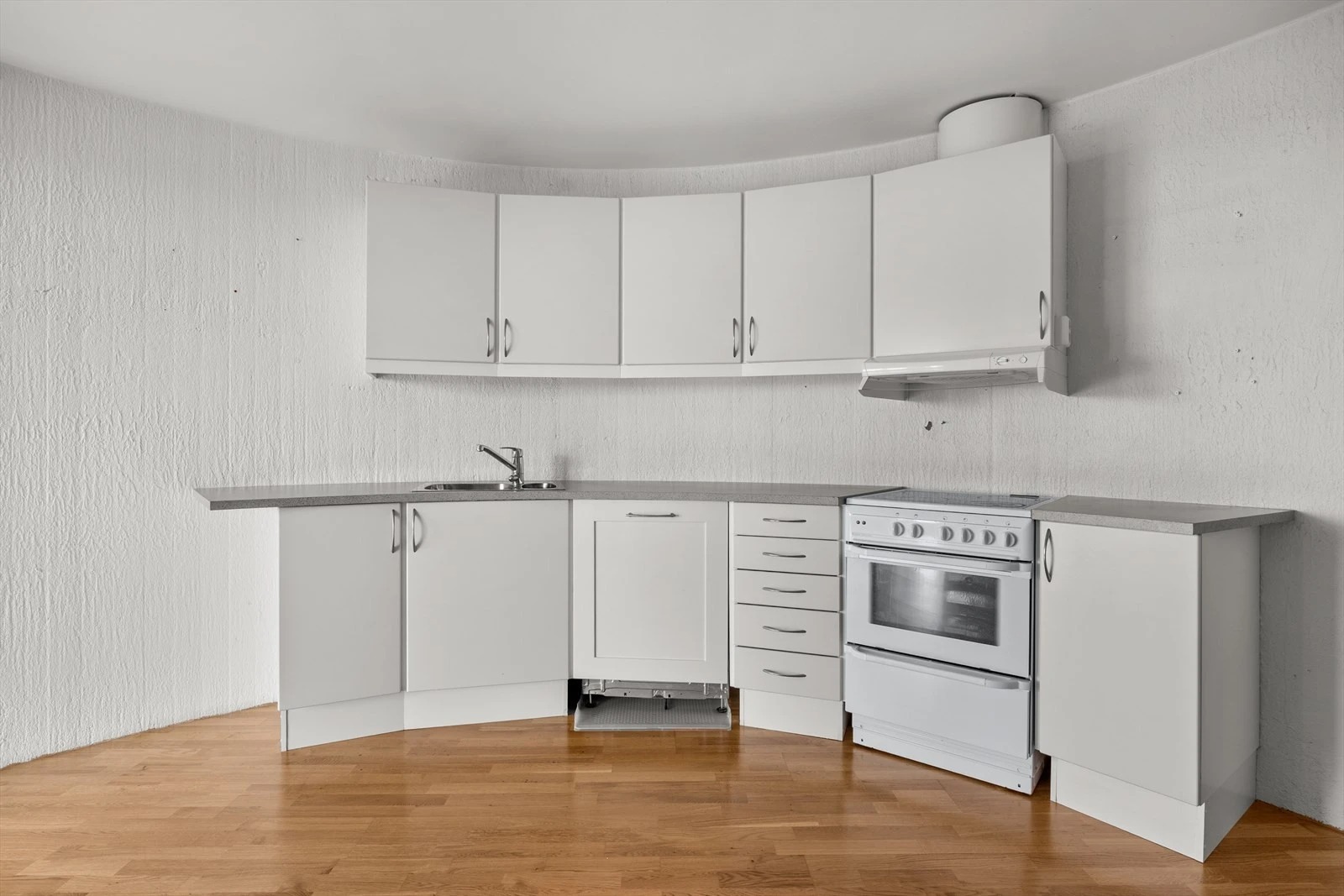Kjøkkeninnredning med integrert oppvaskmaskin og frittstående komfyr. Kjøkkenventilator over stekesone med avtrekk er ført til felles kanaler.
